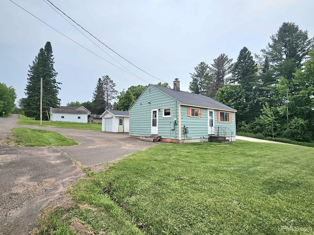 8199 Mill St, Ramsay, MI 49959 - view of home's exterior with a chimney, an outdoor structure, a detached garage, entry steps, and a lawn