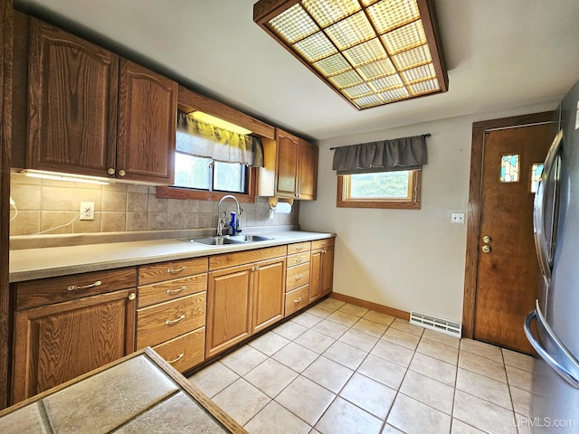 8199 Mill St, Ramsay, MI 49959 - kitchen featuring freestanding refrigerator, light countertops, light tile patterned floors, and plenty of natural light