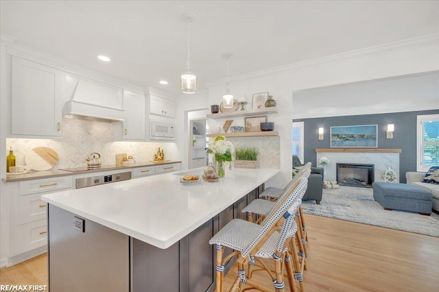 2080 Beaufait Dr, Grosse Pointe Woods, MI 48236 - kitchen with premium range hood, light wood finished floors, white cabinetry, light countertops, and a breakfast bar area