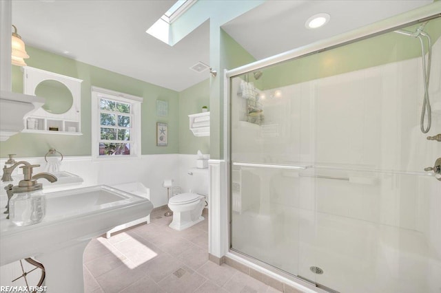 2080 Beaufait Dr, Grosse Pointe Woods, MI 48236 - bathroom featuring a skylight, a shower stall, a wainscoted wall, and tile patterned flooring