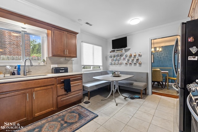 1389 Bedford Rd, Grosse Pointe Park, MI 48230 - kitchen with freestanding refrigerator, crown molding, light countertops, decorative backsplash, and brown cabinetry