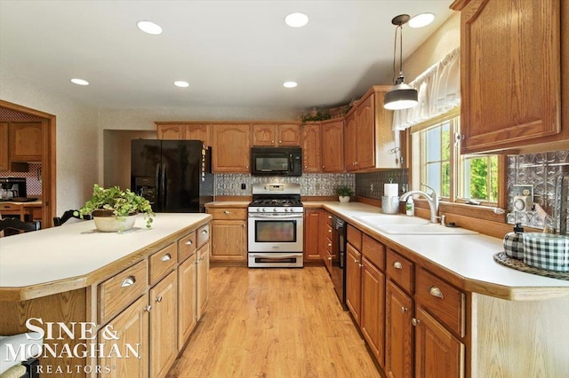 7119 Simons St, Lexington, MI 48450 - kitchen featuring black appliances, light countertops, light wood-style floors, backsplash, and hanging light fixtures