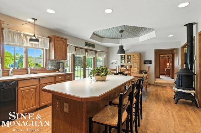 7119 Simons St, Lexington, MI 48450 - kitchen with black dishwasher, a wood stove, light countertops, a center island, and light wood-style floors