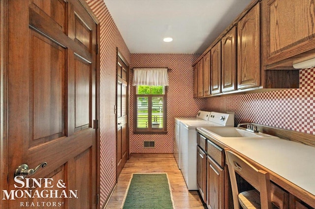 7119 Simons St, Lexington, MI 48450 - laundry room with light wood-style flooring, cabinet space, wallpapered walls, and washer and clothes dryer