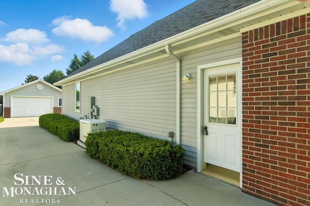 7119 Simons St, Lexington, MI 48450 - view of side of property with an outdoor structure, roof with shingles, a garage, driveway, and brick siding