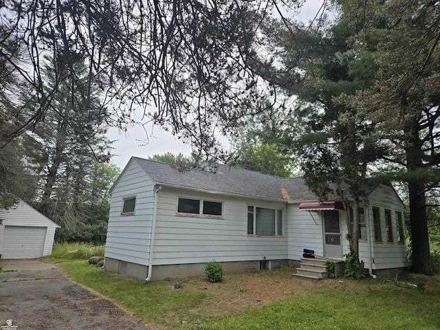 1675 Bauman Rd, Columbus, MI 48063 - back of house featuring an outdoor structure, a shingled roof, driveway, and a detached garage