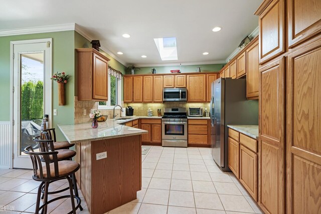 14329 Barton Dr, Washington Twp, MI 48094 - kitchen with appliances with stainless steel finishes, a skylight, a peninsula, crown molding, and light tile patterned floors