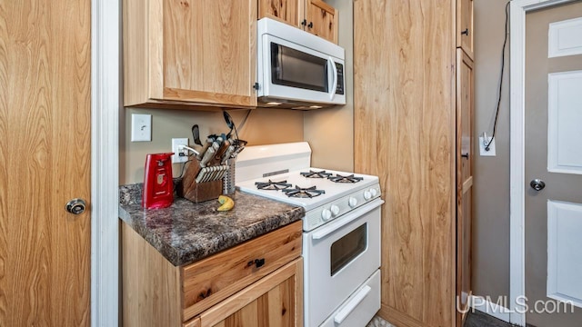 605 S 9th St, Escanaba, MI 49829 - kitchen featuring white appliances, dark countertops, and light brown cabinets