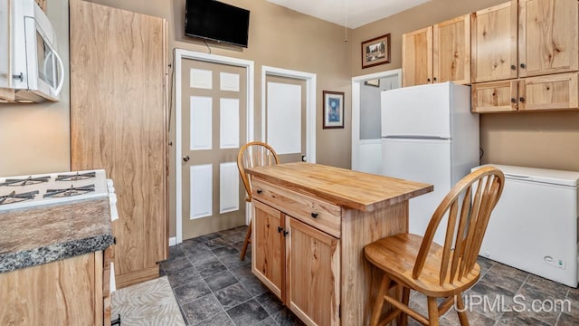 605 S 9th St, Escanaba, MI 49829 - kitchen with white appliances, butcher block counters, light brown cabinets, dark stone finish flooring, and a kitchen island