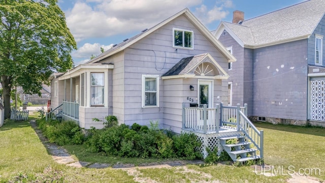 605 S 9th St, Escanaba, MI 49829 - view of front of house with a front lawn, a chimney, and roof with shingles