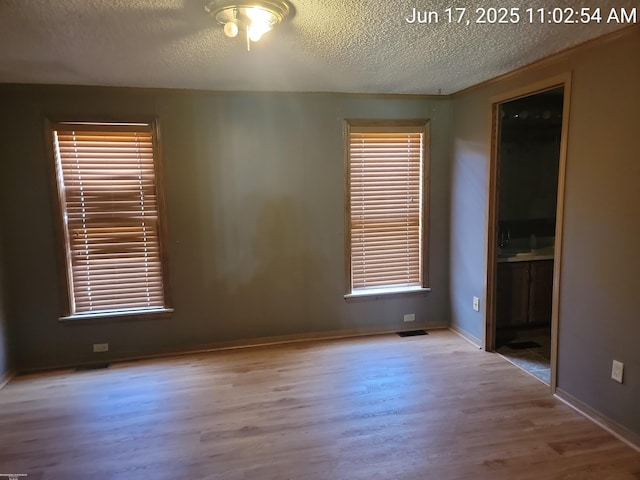 9310 Hill Rd, Wales, MI 48027 - unfurnished bedroom featuring wood finished floors, a textured ceiling, multiple windows, and ensuite bathroom