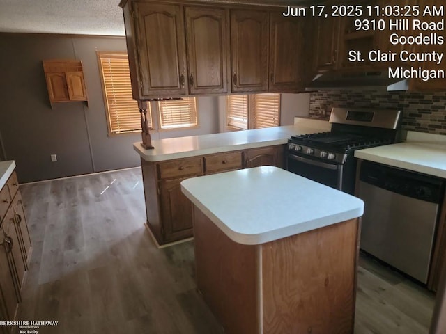 9310 Hill Rd, Wales, MI 48027 - kitchen featuring stainless steel appliances, under cabinet range hood, light countertops, and a peninsula