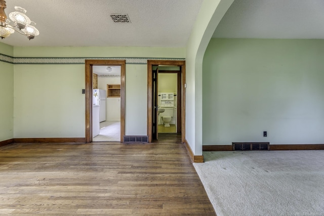6410 Sheridan Line Rd, Croswell, MI 48422 - unfurnished room featuring arched walkways, a chandelier, wood finished floors, and a textured ceiling