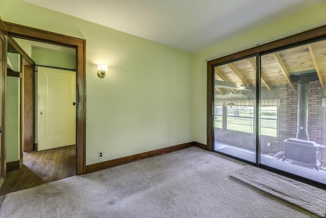 6410 Sheridan Line Rd, Croswell, MI 48422 - carpeted spare room with a wood stove and beam ceiling