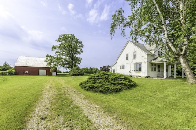 6410 Sheridan Line Rd, Croswell, MI 48422 - view of grassy yard with a garage, driveway, covered porch, and an outbuilding