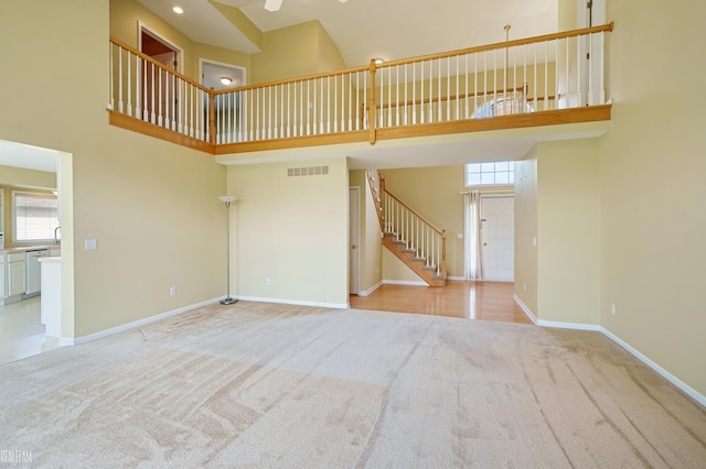 14060 Wayford Run, Shelby Twp, MI 48315 - unfurnished living room with light carpet, a towering ceiling, plenty of natural light, stairway, and a ceiling fan