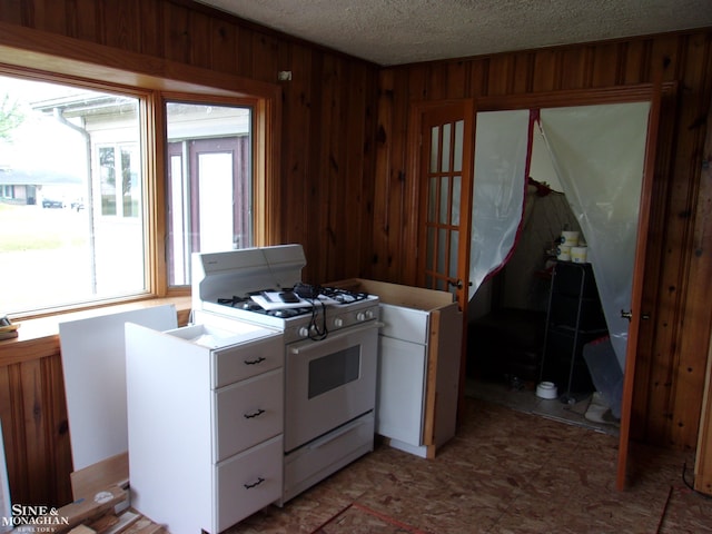 2221 N Channel Dr, Harsens Island, MI 48028 - kitchen with white gas range, white cabinets, wood walls, a textured ceiling, and light countertops