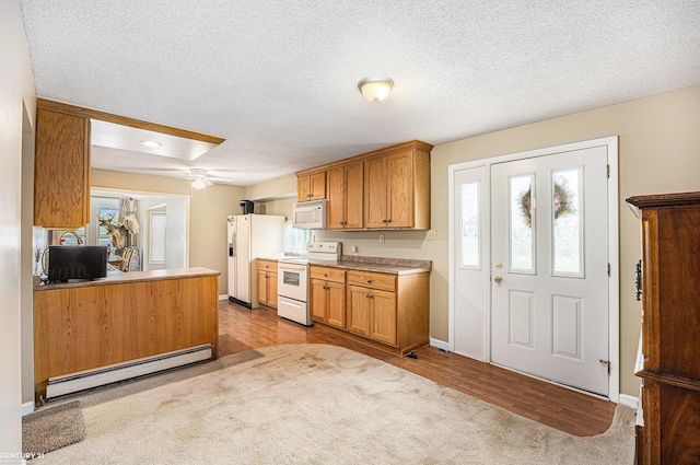 6920 Snover Rd, Decker, MI 48426 - kitchen featuring white appliances, a baseboard heating unit, healthy amount of natural light, brown cabinetry, and a textured ceiling