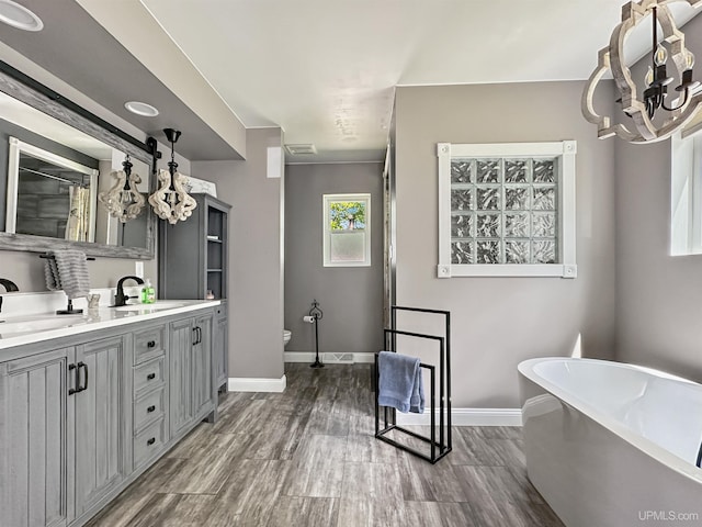 8302 W Burntwood P.15 Dr, Gladstone, MI 49837 - full bathroom with a chandelier, a freestanding tub, double vanity, and wood finished floors