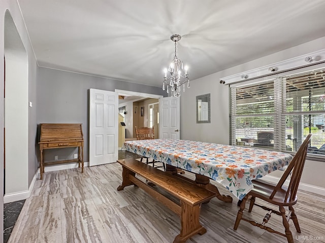 8302 W Burntwood P.15 Dr, Gladstone, MI 49837 - dining area featuring a chandelier, light wood-style floors, and arched walkways