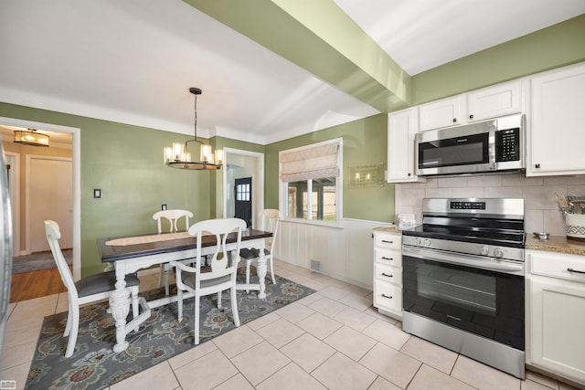 1006 W 12 Mile Rd, Royal Oak, MI 48073 - kitchen featuring stainless steel appliances, a chandelier, white cabinetry, wainscoting, and pendant lighting