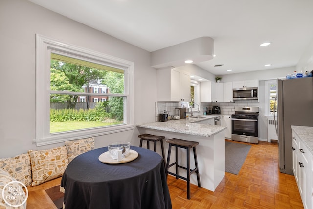 1033 Cadieux Rd, Grosse Pointe, MI 48230 - kitchen featuring appliances with stainless steel finishes, healthy amount of natural light, white cabinets, a peninsula, and recessed lighting