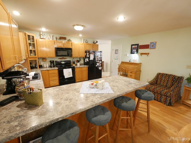 2004 Hunters Ln, Houghton, MI 49931 - kitchen with black appliances, a peninsula, glass insert cabinets, light wood finished floors, and light countertops