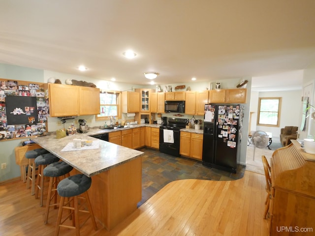 2004 Hunters Ln, Houghton, MI 49931 - kitchen featuring black appliances, a peninsula, light brown cabinets, a kitchen bar, and glass insert cabinets