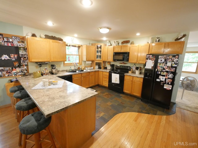 2004 Hunters Ln, Houghton, MI 49931 - kitchen featuring black appliances, a peninsula, a kitchen breakfast bar, light brown cabinets, and healthy amount of natural light