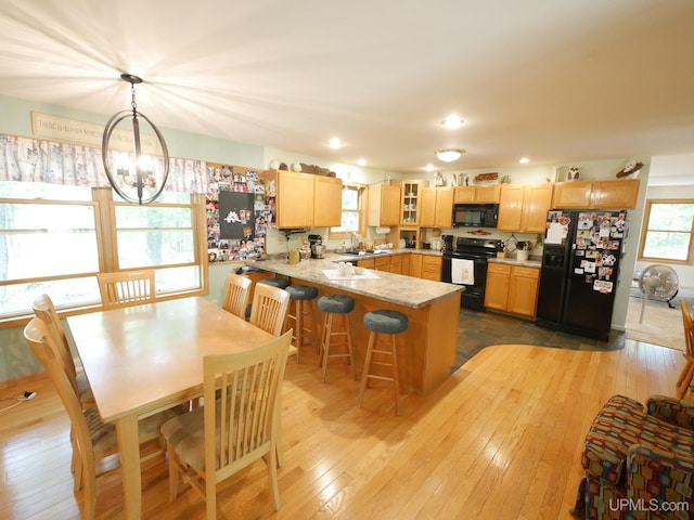 2004 Hunters Ln, Houghton, MI 49931 - kitchen featuring black appliances, a peninsula, light brown cabinetry, glass insert cabinets, and light wood-style floors