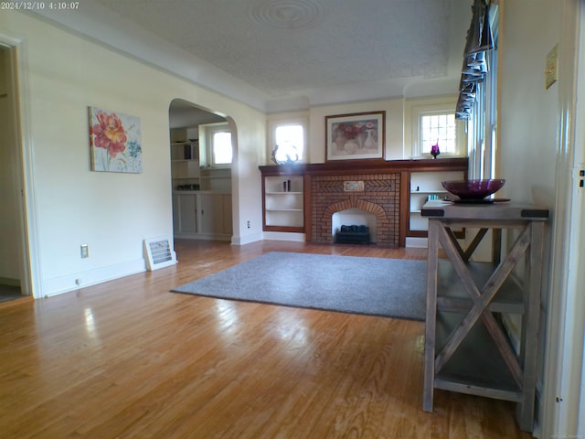 15553 Mclain Ave, Allen Park, MI 48101 - living area with arched walkways, healthy amount of natural light, wood finished floors, a brick fireplace, and a textured ceiling