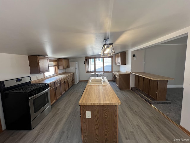 209 N 10th St, Escanaba, MI 49829 - kitchen featuring gas range, a center island with sink, dark wood finished floors, hanging light fixtures, and wood counters