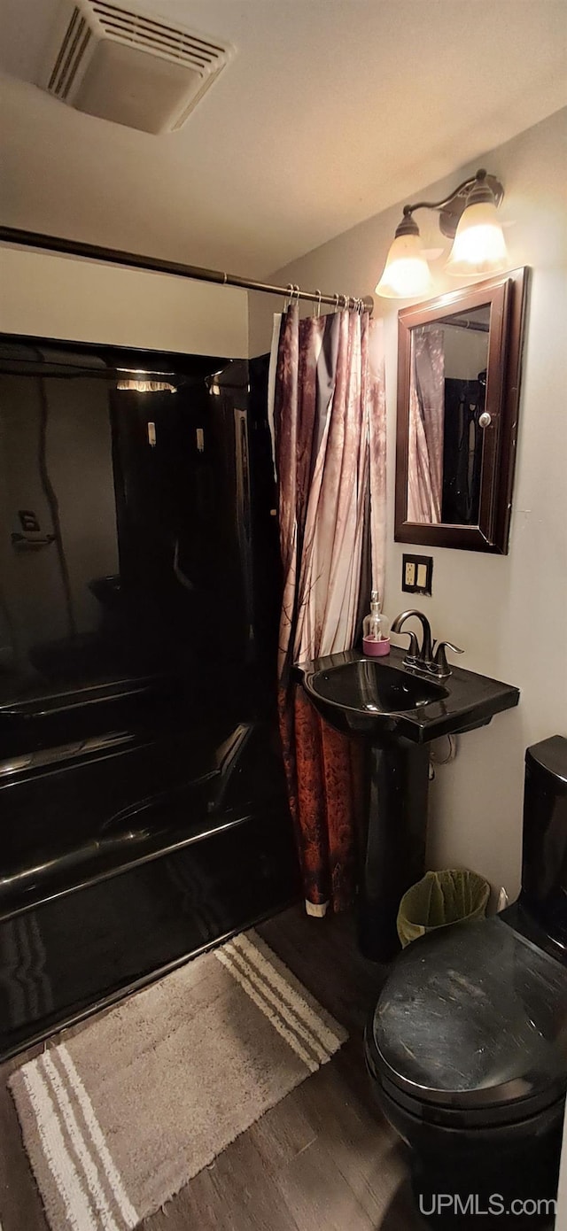 309 Fir St, Munising, MI 49862 - bathroom featuring shower / tub combo with curtain and wood finished floors