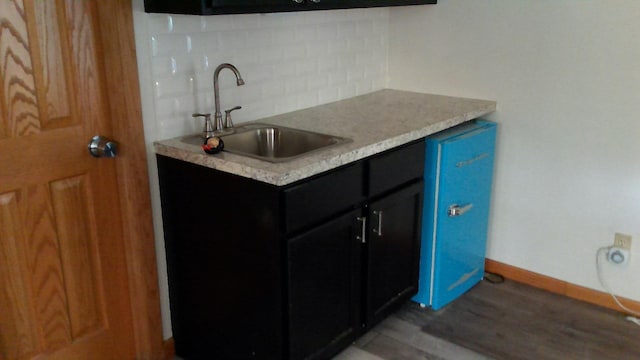 2849 Shaffer Rd, Beaverton, MI 48612 - kitchen featuring backsplash, light wood finished floors, light countertops, and dark cabinetry