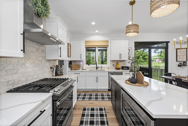 54877 Camden Ct, Shelby Twp, MI 48316 - kitchen with stainless steel appliances, wall chimney range hood, white cabinets, plenty of natural light, and recessed lighting