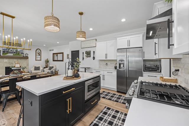 54877 Camden Ct, Shelby Twp, MI 48316 - kitchen with stainless steel appliances, ventilation hood, white cabinets, backsplash, and recessed lighting