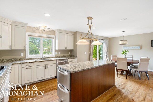 1001 Lake Shore Rd, Grosse Pointe Shores, MI 48236 - kitchen with light wood-style flooring, a kitchen island, decorative light fixtures, light stone countertops, and white cabinetry