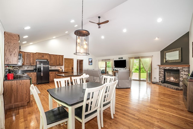 6242 N Geneva Rd, Coleman, MI 48618 - dining room featuring high vaulted ceiling, a fireplace, a ceiling fan, and light wood-style floors