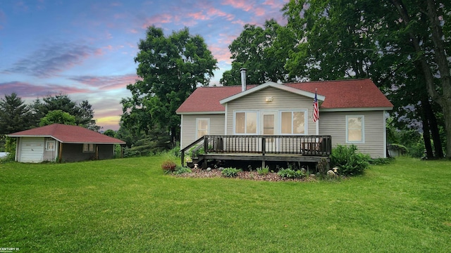 4467 Kings Corner Rd, Glennie, MI 48737 - back of house at dusk featuring a deck, a yard, a detached garage, and an outdoor structure