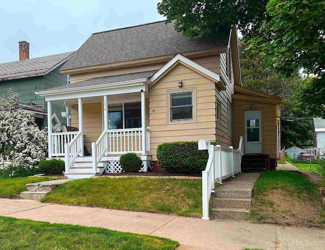 206 Cherry St, Munising, MI 49862 - bungalow-style house with a porch, roof with shingles, and a front yard