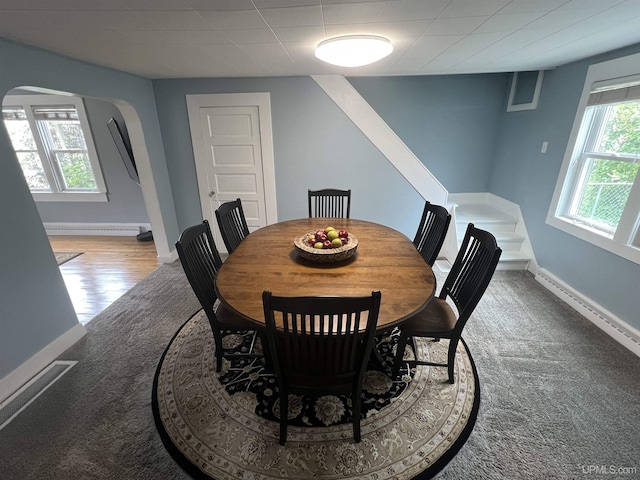 206 Cherry St, Munising, MI 49862 - carpeted dining area with arched walkways, stairs, and a baseboard heating unit
