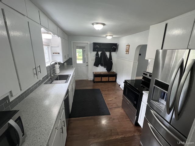 206 Cherry St, Munising, MI 49862 - kitchen with appliances with stainless steel finishes, arched walkways, a wainscoted wall, dark wood finished floors, and backsplash