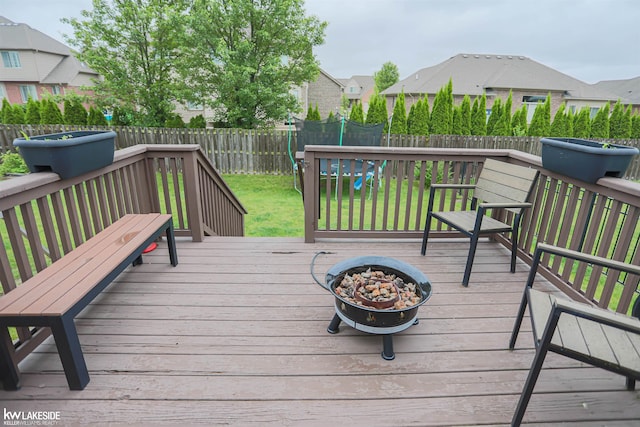 56798 Winding Creek Dr, Macomb, MI 48042 - wooden terrace with a fire pit, a fenced backyard, and a trampoline