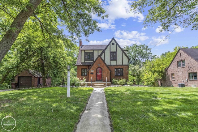 35727 Elm St, Wayne, MI 48184 - tudor house with a chimney, brick siding, a front yard, and a detached garage