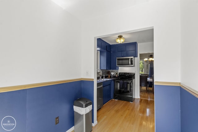 35727 Elm St, Wayne, MI 48184 - kitchen with appliances with stainless steel finishes, light wood-style floors, a chandelier, blue cabinets, and tasteful backsplash