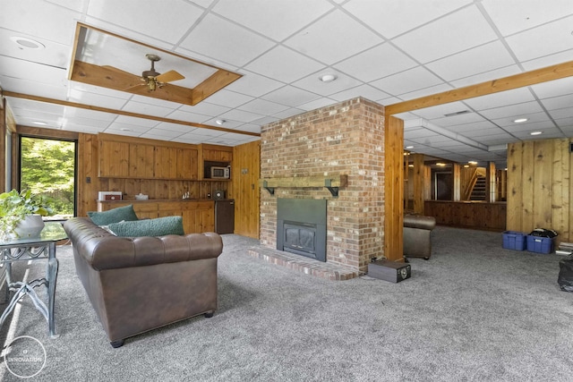 35727 Elm St, Wayne, MI 48184 - living room featuring wooden walls, carpet floors, a drop ceiling, ceiling fan, and a brick fireplace
