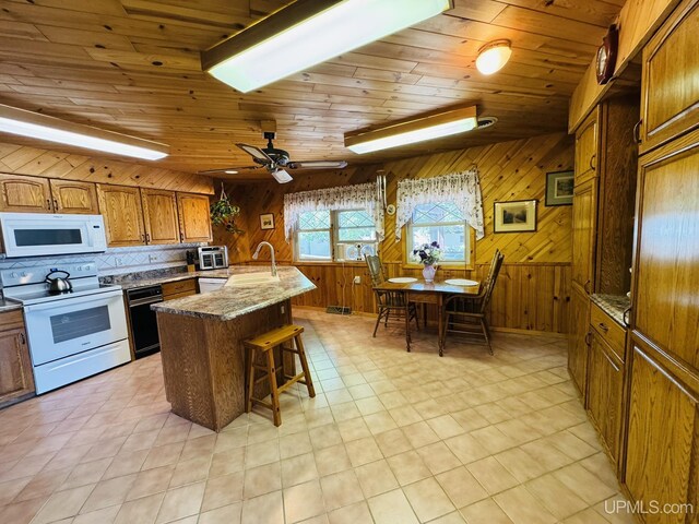 292 Chestnut St, Kingsford, MI 49802 - kitchen with white appliances, brown cabinets, wood ceiling, a kitchen breakfast bar, and wood walls