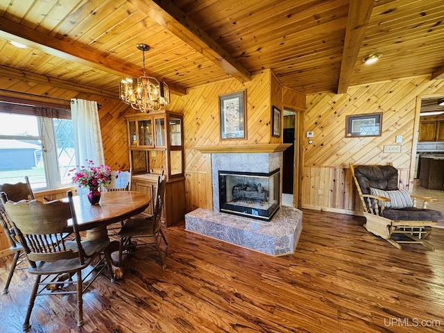 292 Chestnut St, Kingsford, MI 49802 - dining space with hardwood / wood-style flooring, a glass covered fireplace, wooden walls, a chandelier, and a wooden ceiling with exposed beams