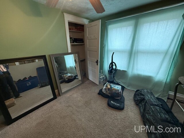 E2903 H44 Rd, Traunik, MI 49891 - bedroom featuring carpet floors, ceiling fan, a textured ceiling, and a baseboard heating unit