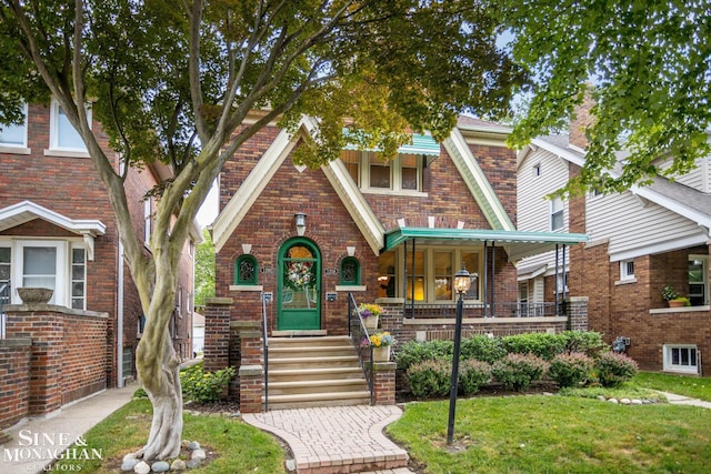 1258-1260 Lakepointe St, Grosse Pointe, MI 48230 - tudor-style house with brick siding, a front yard, and a porch